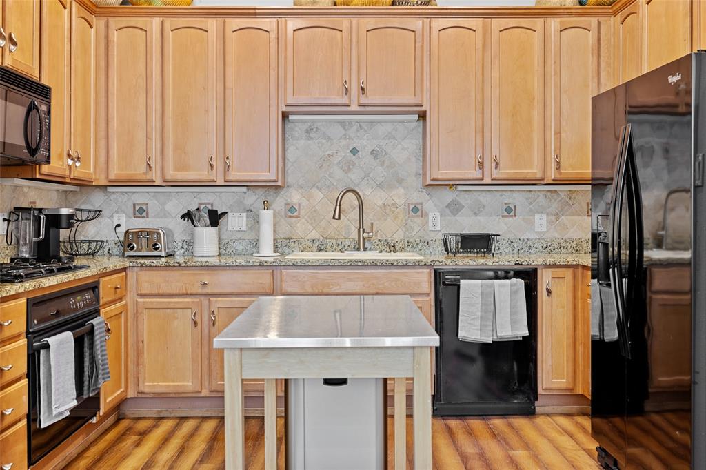 4312 McKinney Avenue, Unit 4 Dallas, TX 75205 - Photo 8 of 34 Kitchen featuring black appliances, light wood-type flooring, light stone counters, tasteful backsplash, and light brown cabinets