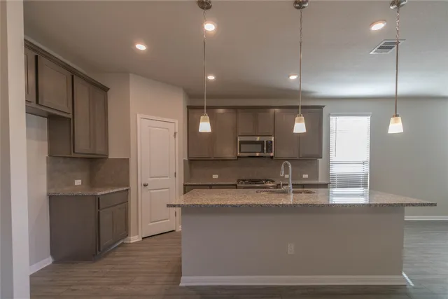 a kitchen with kitchen island a counter top space a sink stainless steel appliances and cabinets