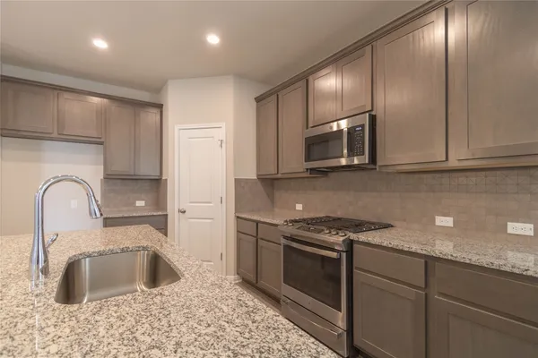 a kitchen with granite countertop a sink stainless steel appliances and cabinets