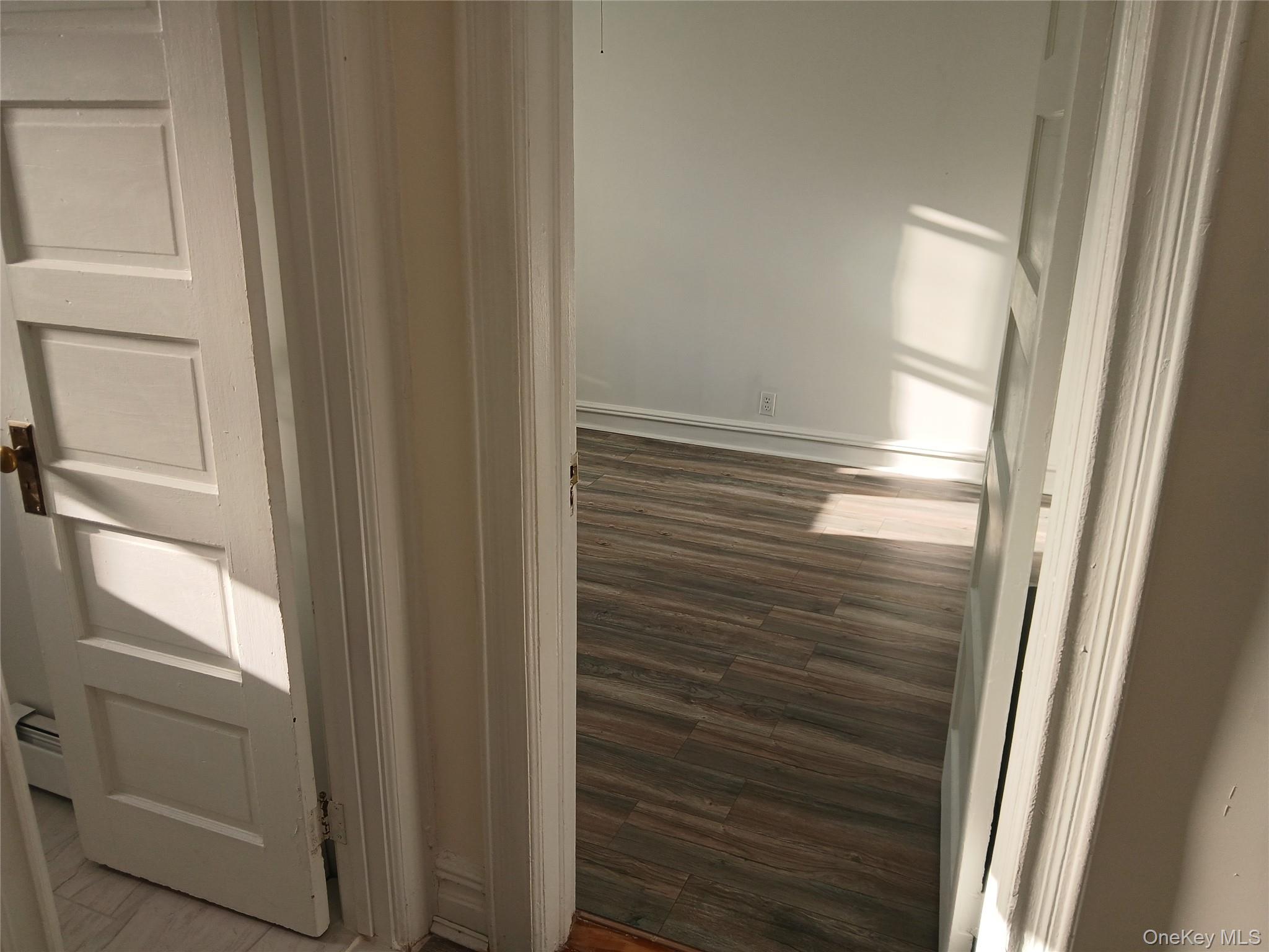 88-10 78th Street Queens, NY 11421 - Photo 4 of 12 Hall with dark wood-style floors and a baseboard heating unit