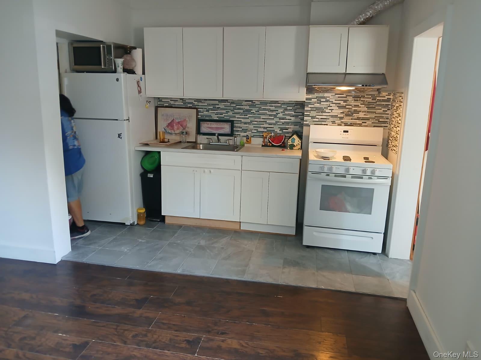 88-10 78th Street Queens, NY 11421 - Photo 10 of 12 Kitchen with white appliances, light countertops, white cabinetry, and tasteful backsplash