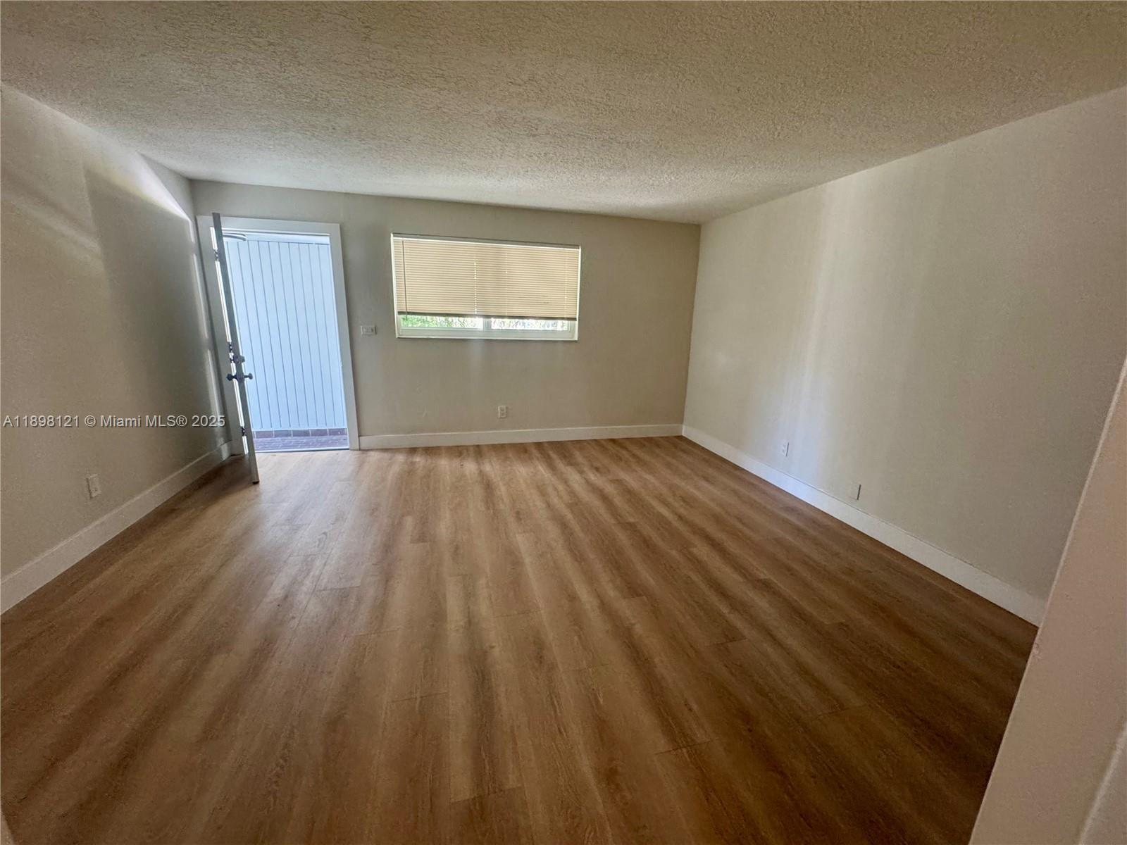 6805 Southwest 88th Street, Unit 12 Pinecrest, FL 33156 - Photo 5 of 18 wooden floor in an empty room with a window