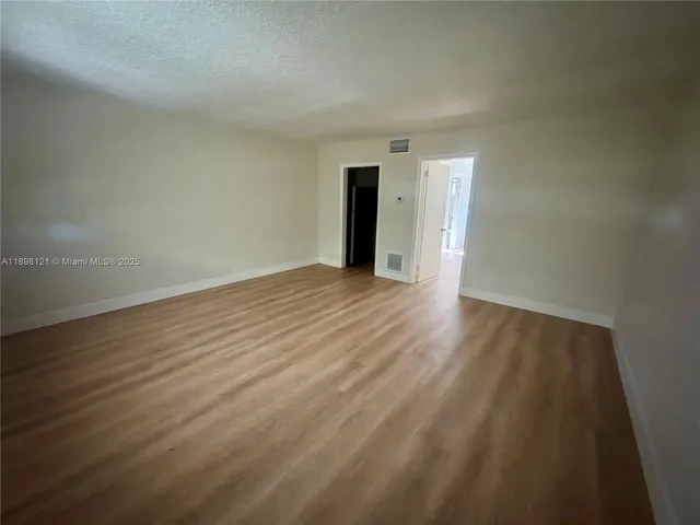 a view of an empty room with wooden floor