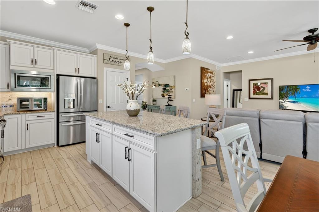 5215 Ciatto Way Ave Maria, FL 34142 - Photo 46 of 46 a kitchen with granite countertop a stove a sink a kitchen island with stainless steel appliances cabinets and a wooden floor
