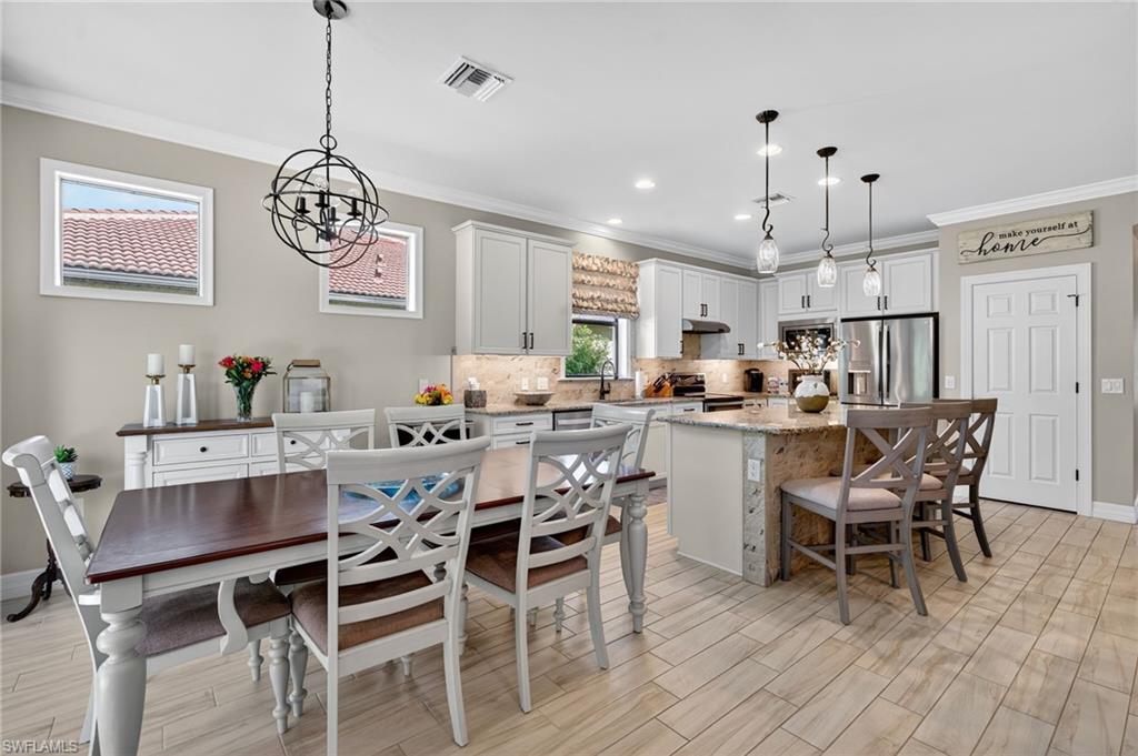 5215 Ciatto Way Ave Maria, FL 34142 - Photo 6 of 46 a dining room with stainless steel appliances kitchen island a table and chairs