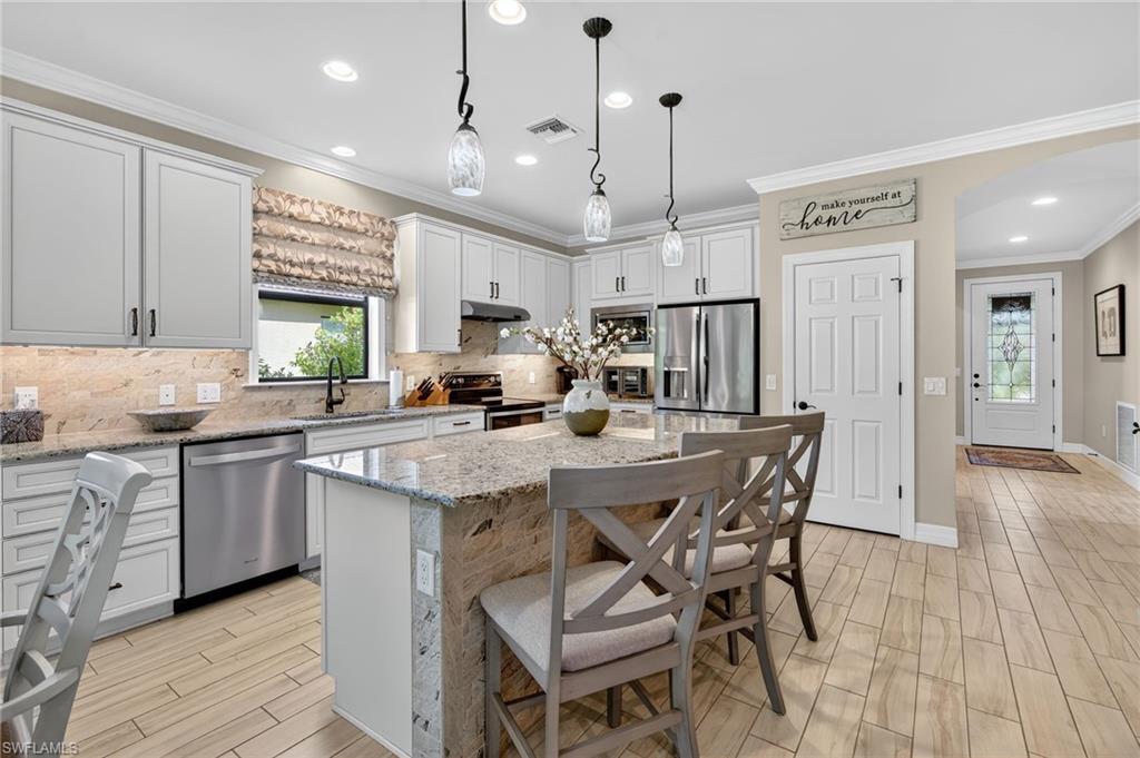 5215 Ciatto Way Ave Maria, FL 34142 - Photo 7 of 46 a kitchen with stainless steel appliances granite countertop a stove a sink a refrigerator a center island and a cabinets