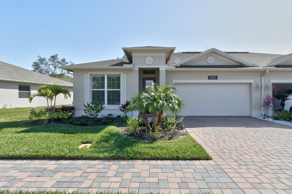 5967 Bella Rosa Lane Vero Beach, FL 32966 - Photo 1 of 30 a front view of a house with a yard and potted plants