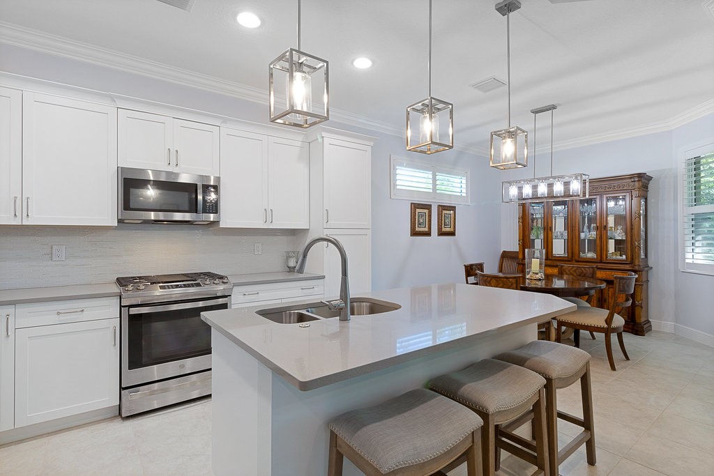 5967 Bella Rosa Lane Vero Beach, FL 32966 - Photo 8 of 30 a kitchen with a sink a stove and chairs
