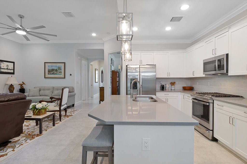 5967 Bella Rosa Lane Vero Beach, FL 32966 - Photo 9 of 30 a kitchen with stainless steel appliances kitchen island granite countertop a sink a stove a refrigerator cabinets and chairs