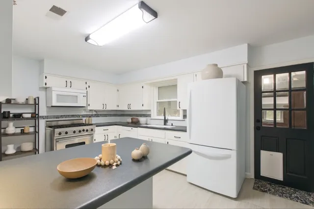 a kitchen with white cabinets and appliances