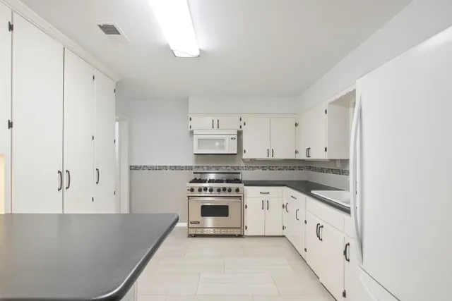 a kitchen with granite countertop white cabinets and appliances