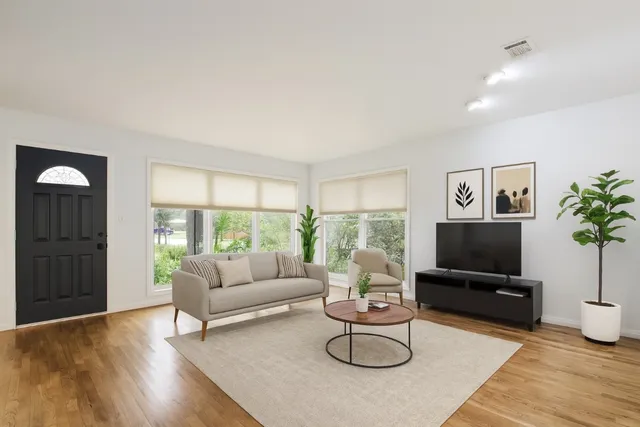 a living room with furniture a flat screen tv and a large window