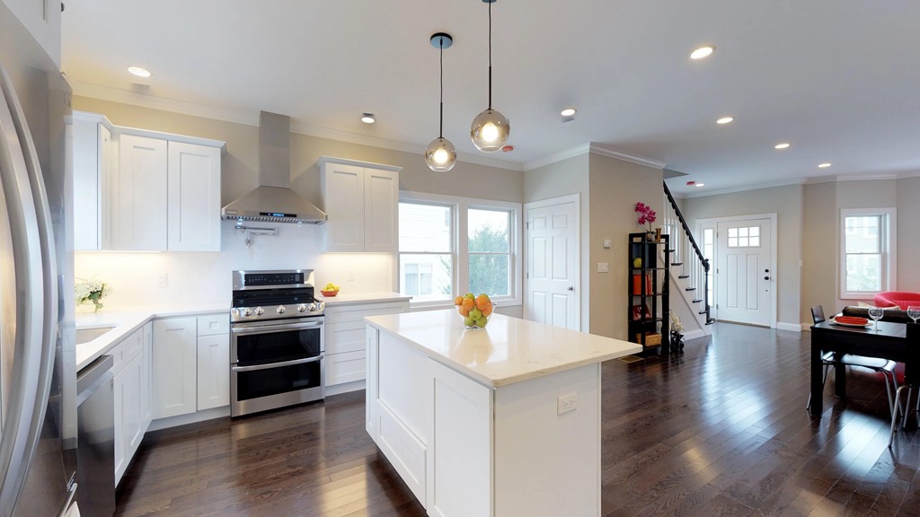 11 Sunset Road, Unit 2 Cambridge, MA 02138 - Photo 15 of 29 a kitchen with stainless steel appliances kitchen island granite countertop a stove a sink a refrigerator and white cabinets with wooden floor