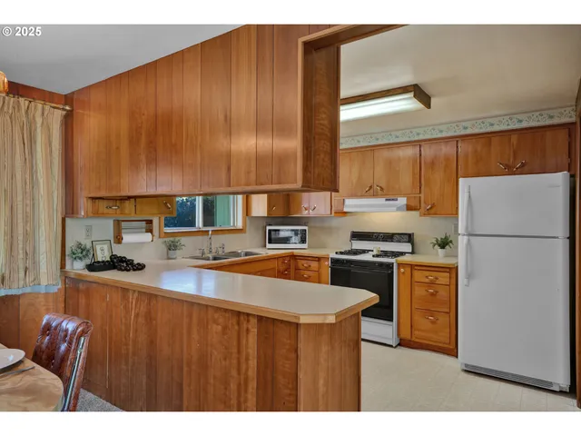 a kitchen with stainless steel appliances granite countertop a refrigerator a sink dishwasher a stove with white cabinets and wooden floor