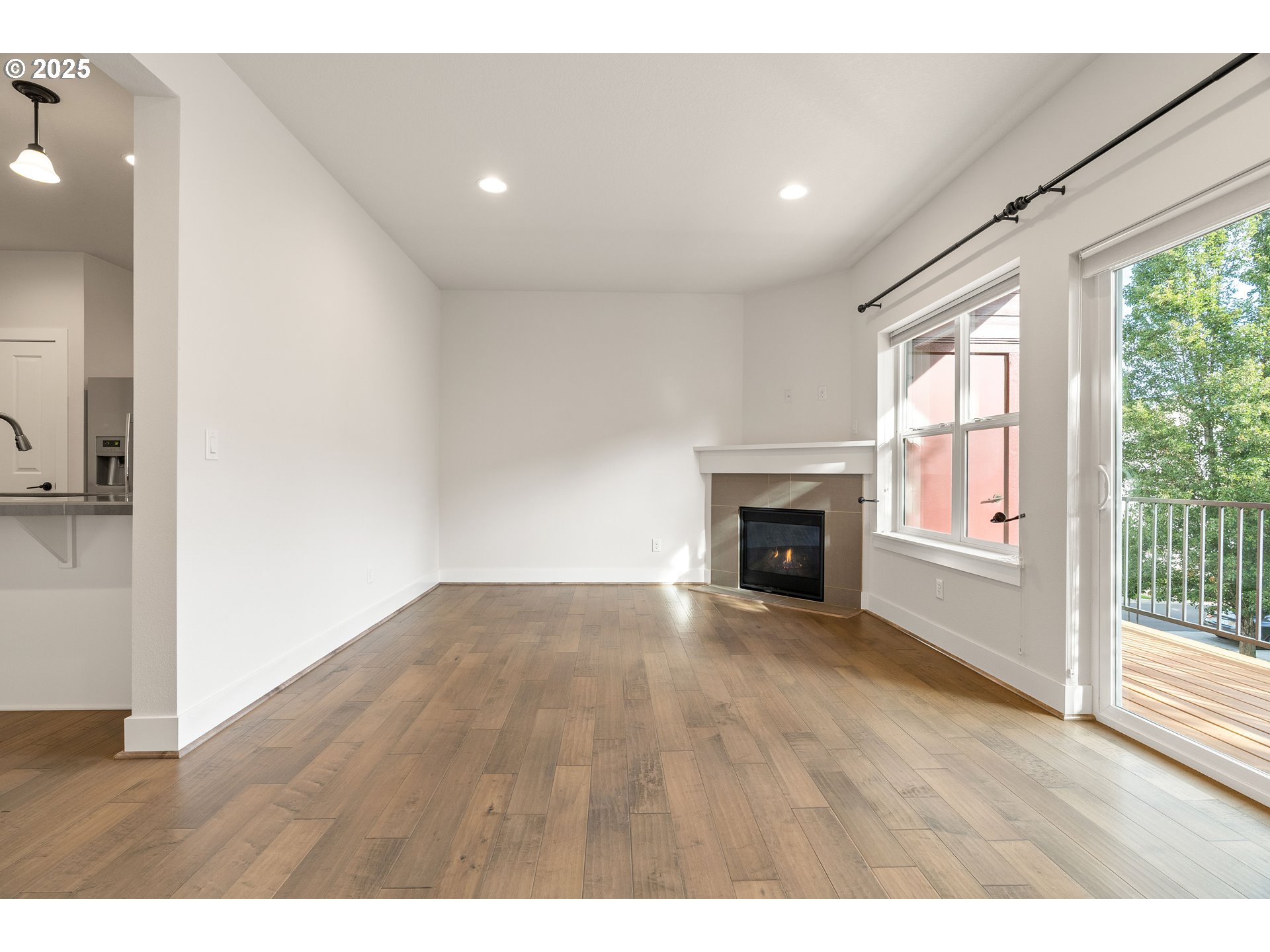 15664 Southwest Ivory Street Beaverton, OR 97007 - Photo 6 of 40 a view of an empty room with wooden floor fireplace and a window