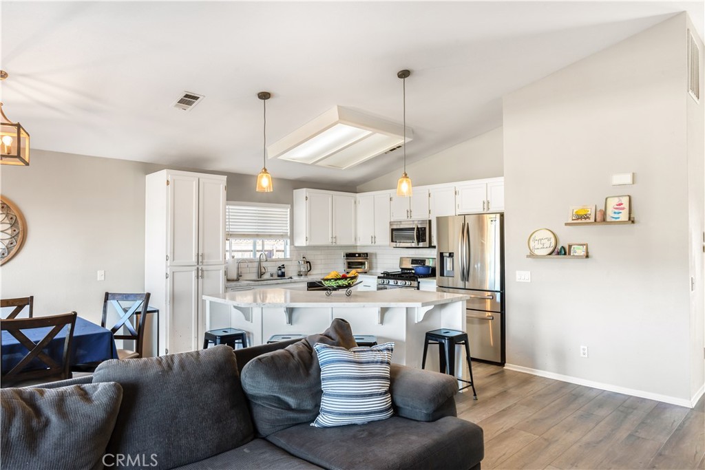33012 Tulley Ranch Road Temecula, CA 92592 - Photo 10 of 25 a kitchen with stainless steel appliances kitchen island granite countertop a refrigerator a stove a sink dishwasher a dining table and chairs with wooden floor