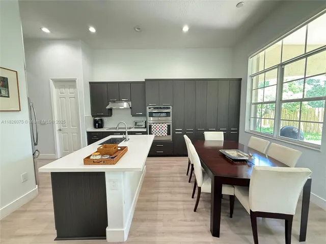 a kitchen with a table chairs a sink dishwasher refrigerator and cabinets