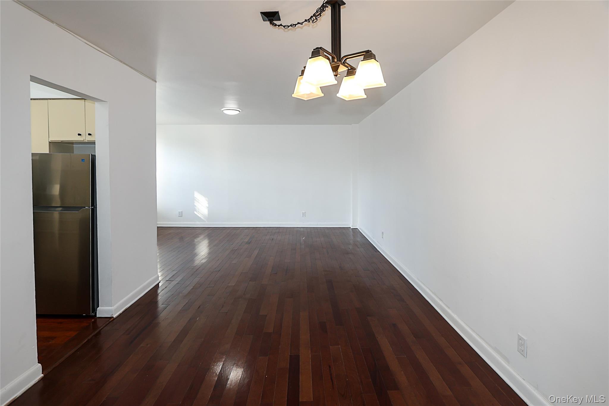 47-22 215th Place, Unit 2C Queens, NY 11361 - Photo 5 of 26 Unfurnished dining area with dark wood finished floors and a chandelier