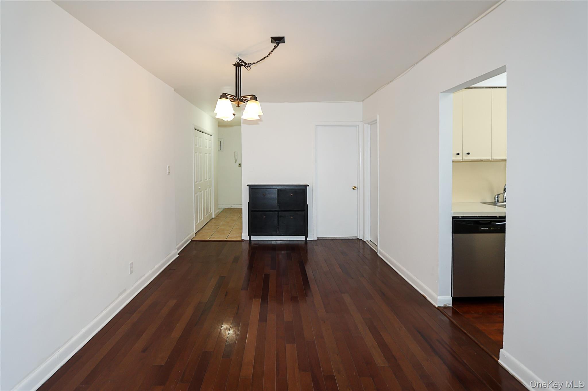 47-22 215th Place, Unit 2C Queens, NY 11361 - Photo 8 of 26 Unfurnished living room featuring a chandelier and dark wood-type flooring
