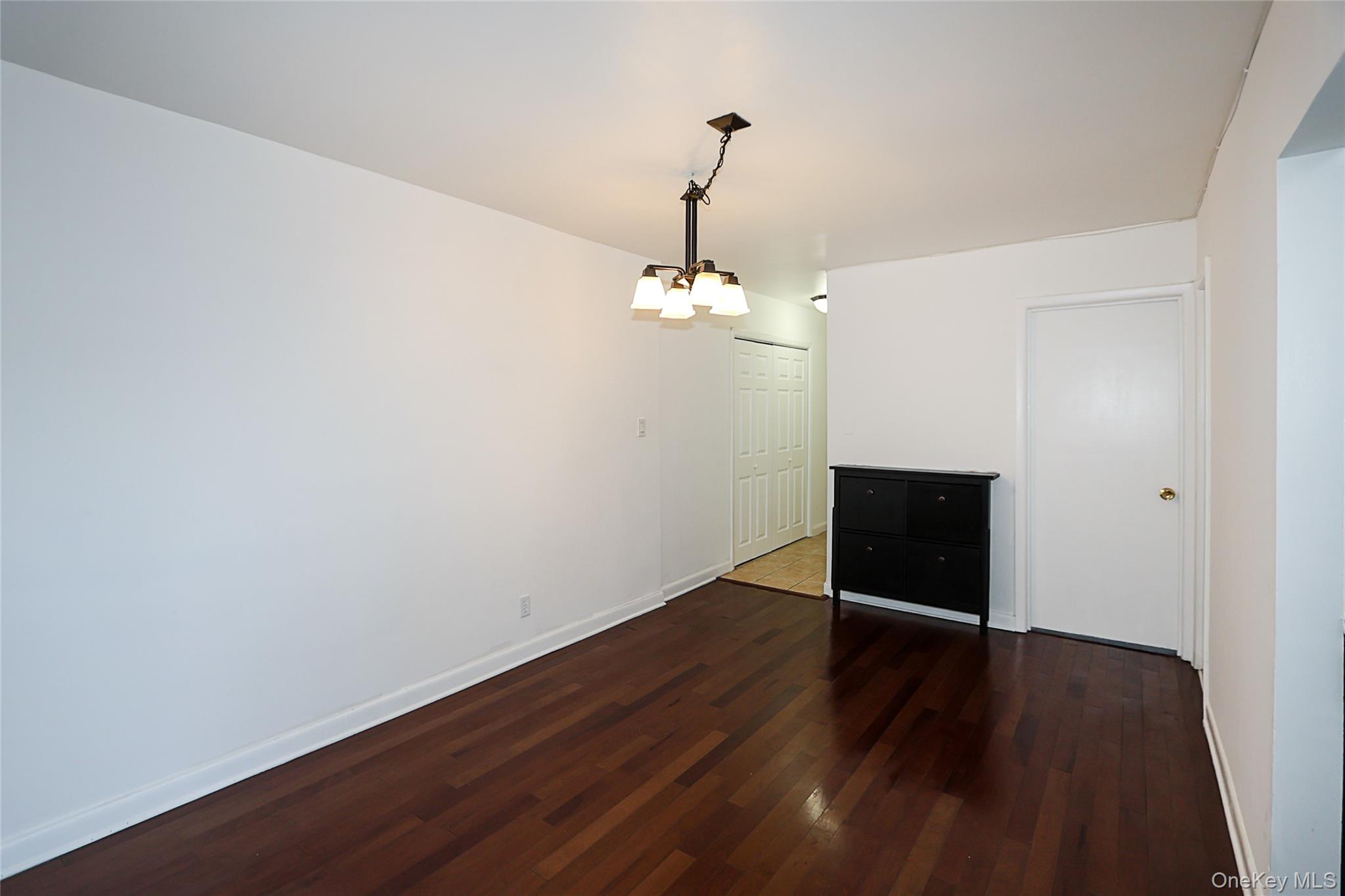 47-22 215th Place, Unit 2C Queens, NY 11361 - Photo 9 of 26 Unfurnished dining area featuring dark wood-style floors and a chandelier