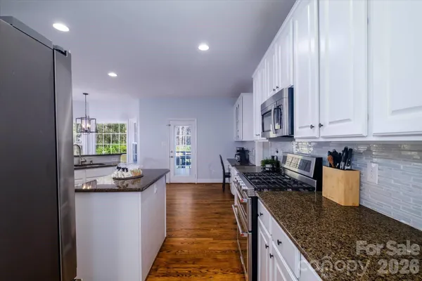 a kitchen with stainless steel appliances granite countertop a sink stove and refrigerator
