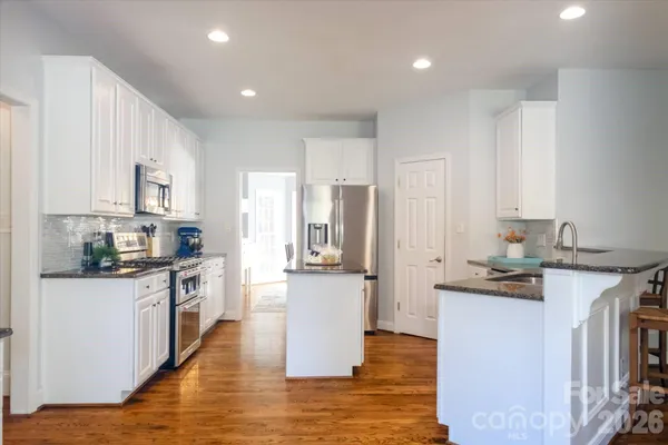 a kitchen with stainless steel appliances granite countertop a refrigerator and a stove top oven
