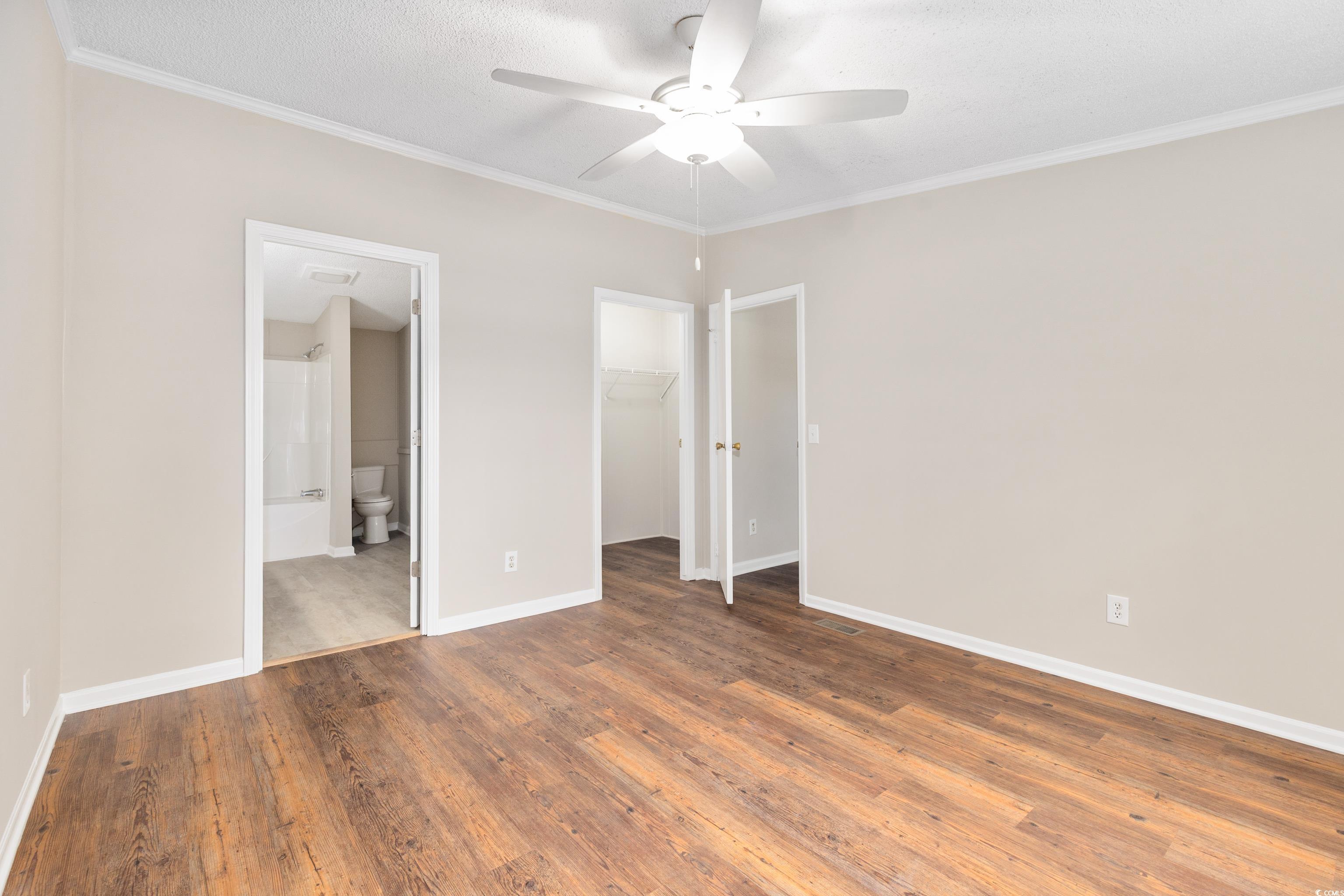 3106 Dog Bluff Road Aynor, SC 29511 - Photo 13 of 27 Unfurnished bedroom featuring ornamental molding, wood finished floors, a spacious closet, a ceiling fan, and a textured ceiling