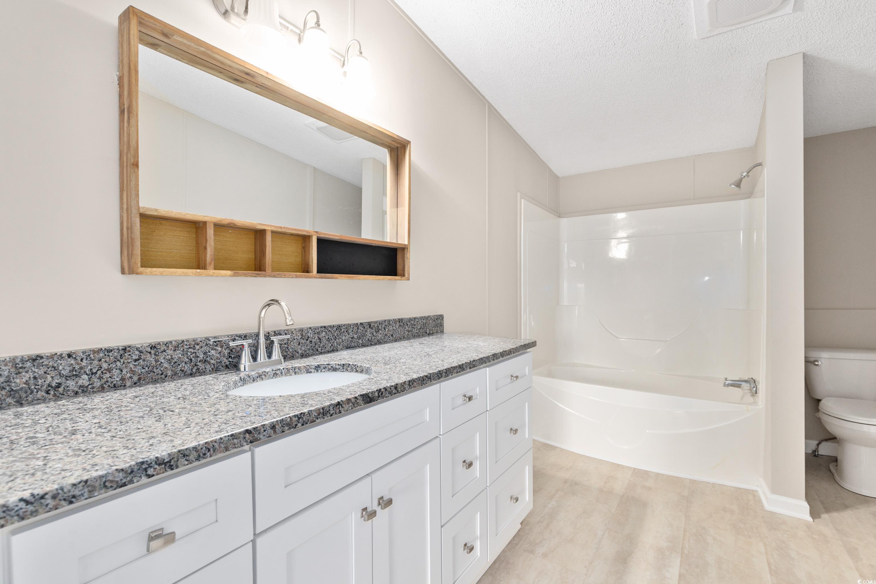 3106 Dog Bluff Road Aynor, SC 29511 - Photo 14 of 27 Bathroom featuring vanity, a textured ceiling, shower combination, and light wood-style floors