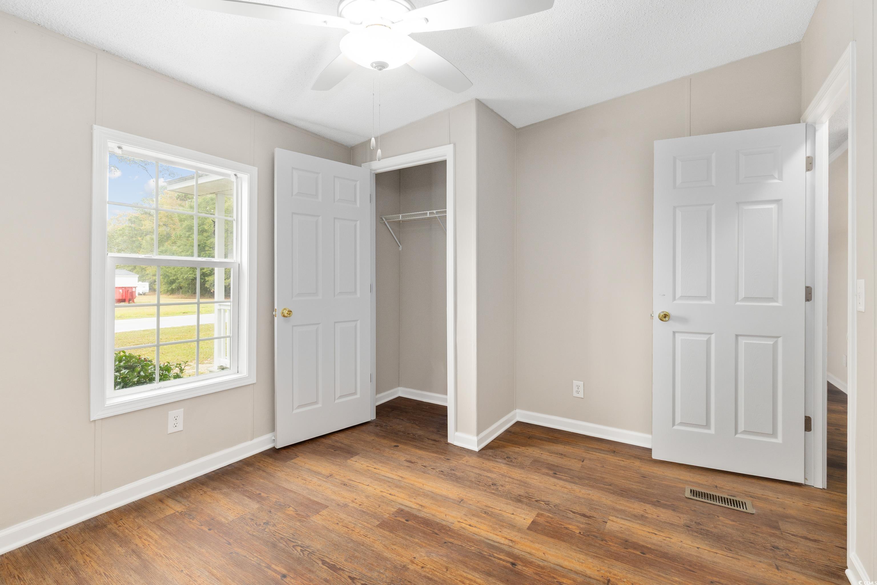 3106 Dog Bluff Road Aynor, SC 29511 - Photo 18 of 27 Unfurnished bedroom with a closet, wood finished floors, and a ceiling fan