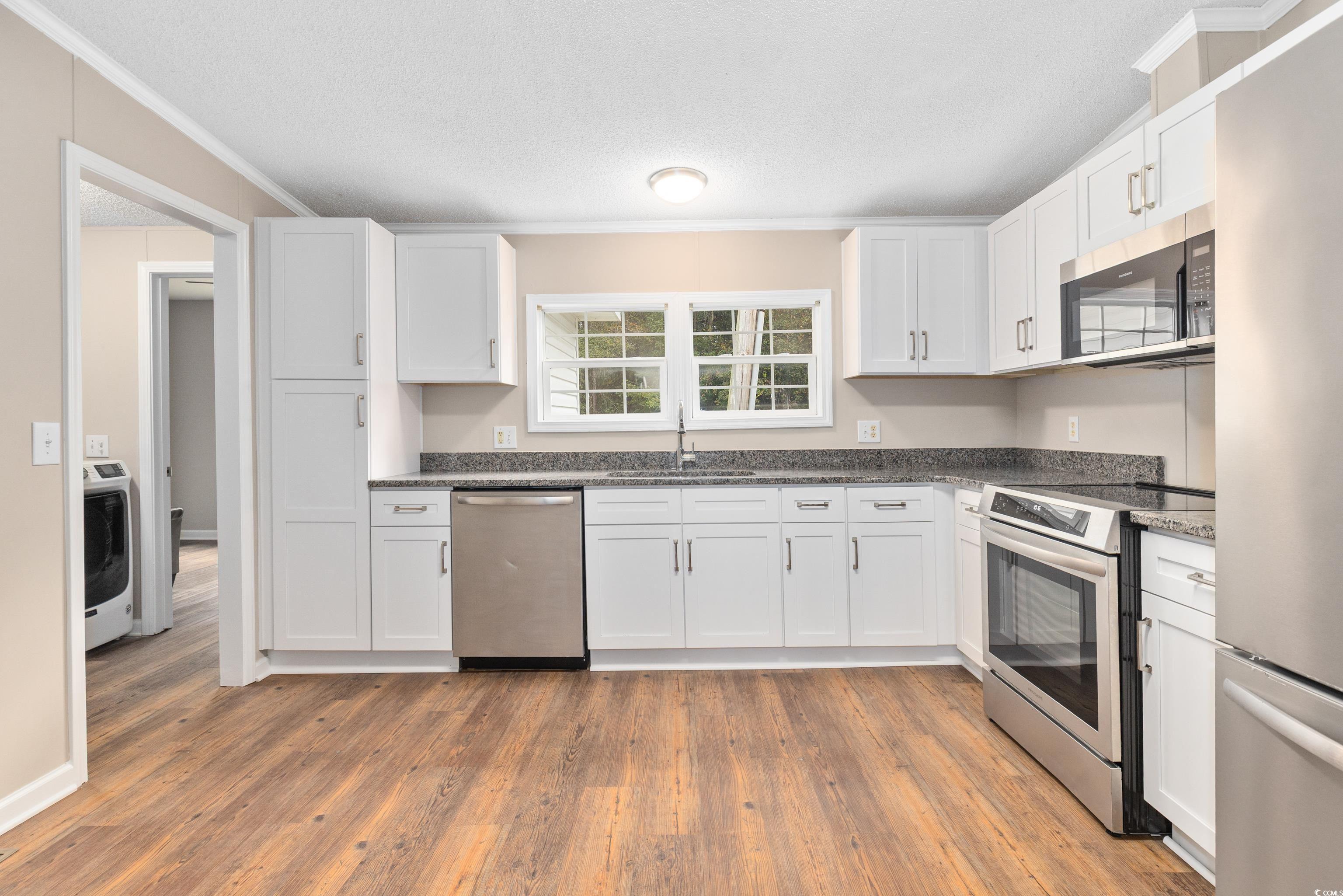 3106 Dog Bluff Road Aynor, SC 29511 - Photo 3 of 27 Kitchen with appliances with stainless steel finishes, white cabinets, light wood finished floors, a textured ceiling, and crown molding