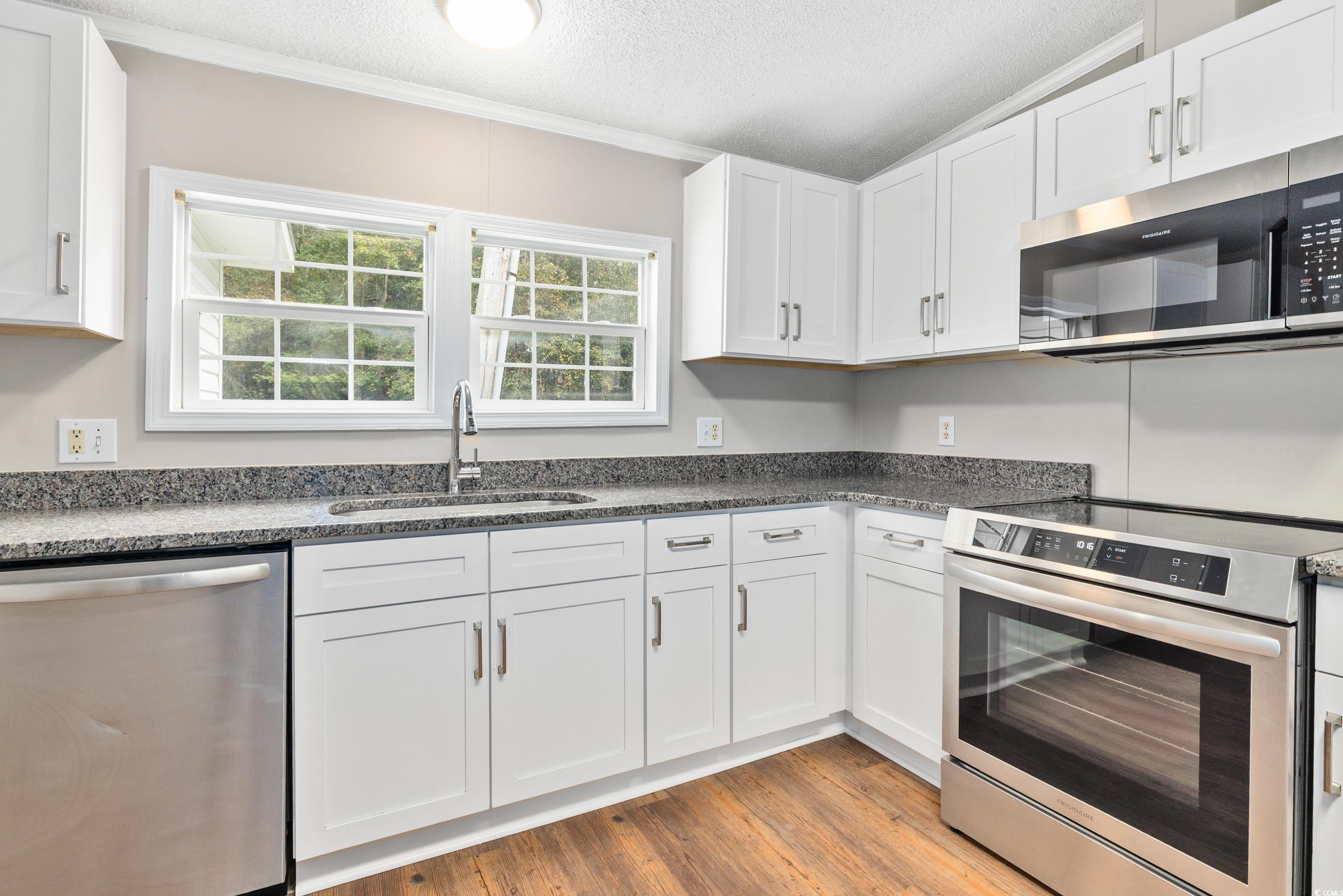 3106 Dog Bluff Road Aynor, SC 29511 - Photo 4 of 27 Kitchen with stainless steel appliances, light wood-style flooring, white cabinetry, dark stone countertops, and a textured ceiling