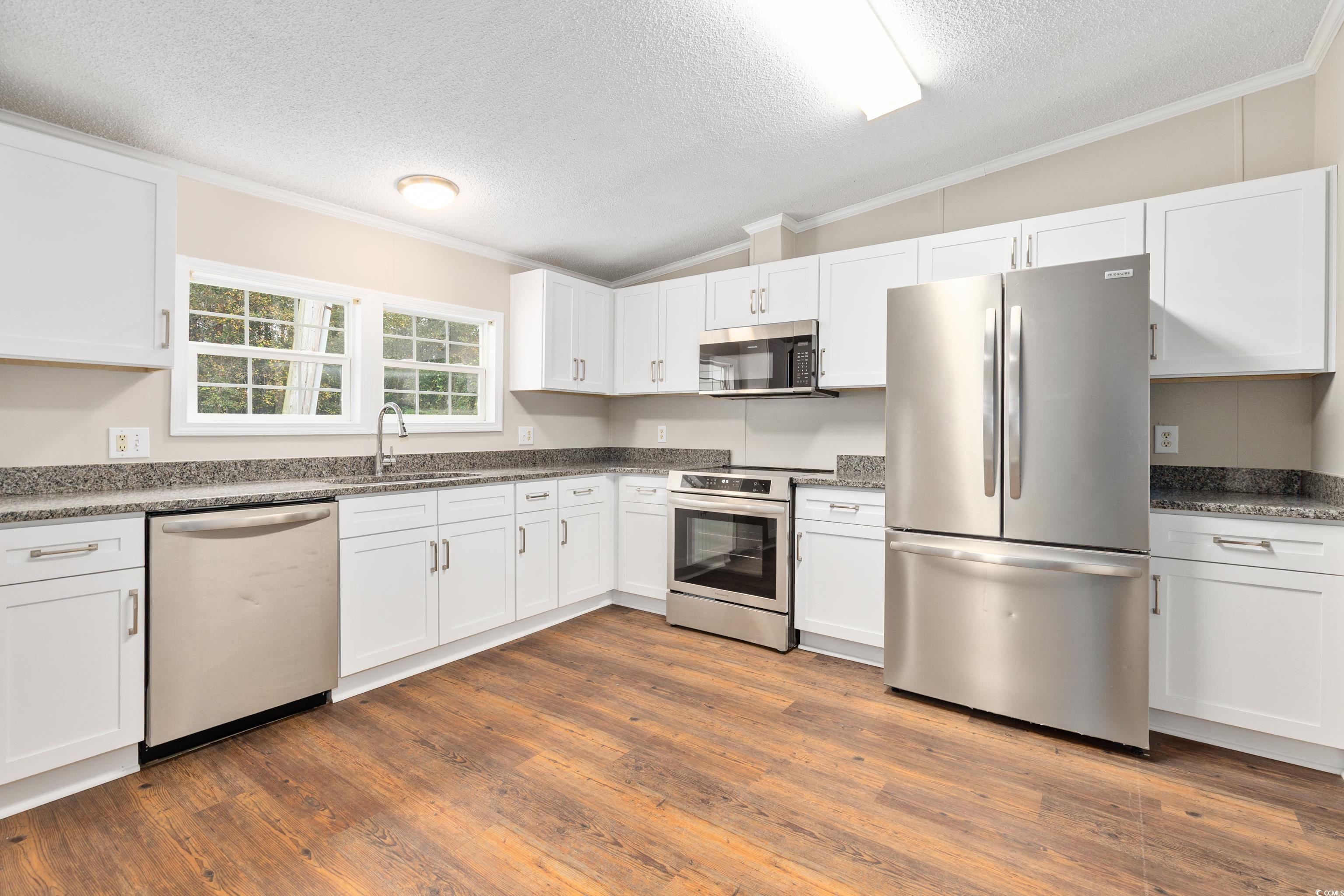 3106 Dog Bluff Road Aynor, SC 29511 - Photo 5 of 27 Kitchen featuring stainless steel appliances, ornamental molding, a textured ceiling, white cabinetry, and dark stone counters
