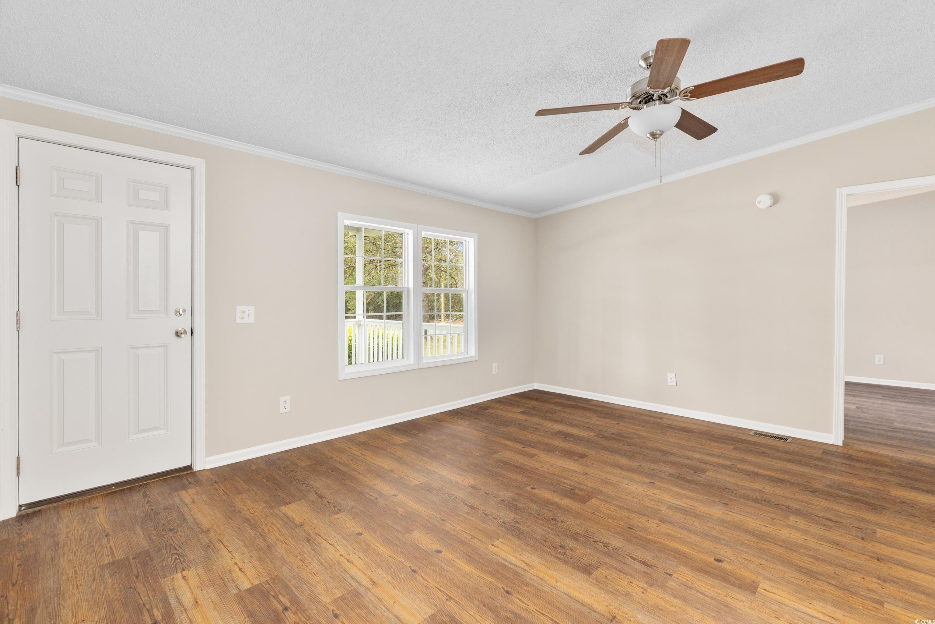 3106 Dog Bluff Road Aynor, SC 29511 - Photo 8 of 27 Unfurnished living room with crown molding, dark wood finished floors, a textured ceiling, and a ceiling fan