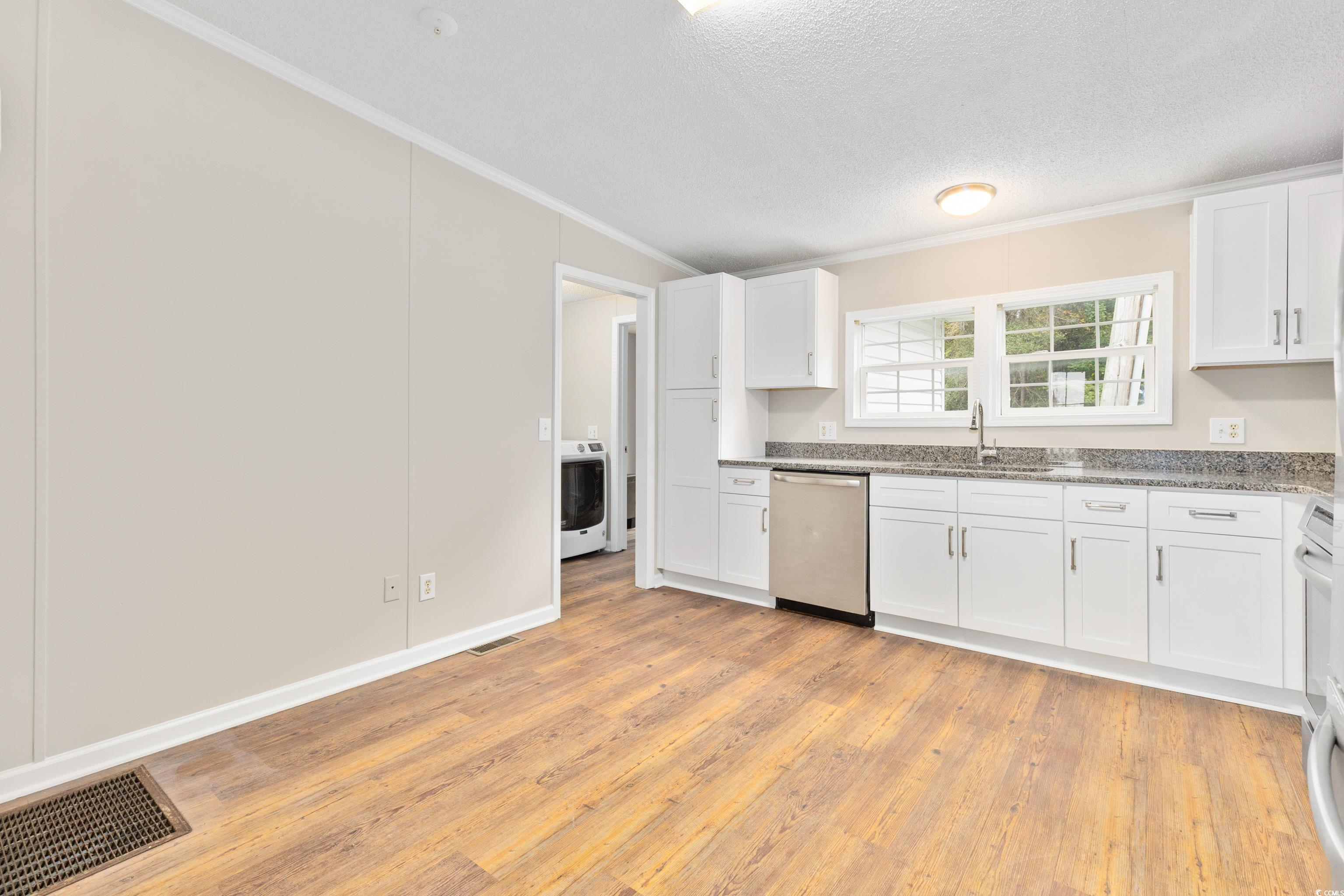 3106 Dog Bluff Road Aynor, SC 29511 - Photo 9 of 27 Kitchen featuring ornamental molding, white cabinetry, light wood finished floors, stainless steel dishwasher, and light stone counters