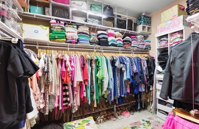 a view of walk in closet with clothes and shoes