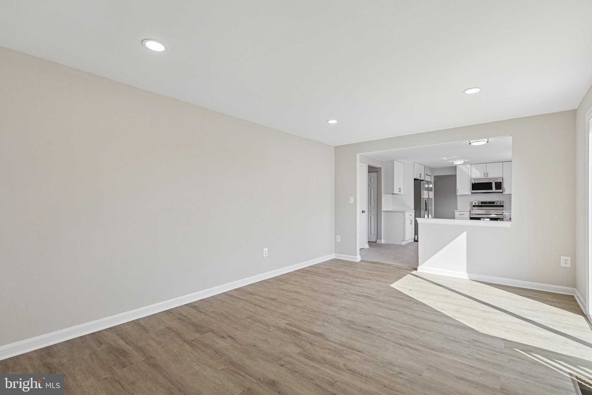 7451 Oakland Mills Road Columbia, MD 21046 - Photo 36 of 83 a view of an empty room with wooden floor and a kitchen