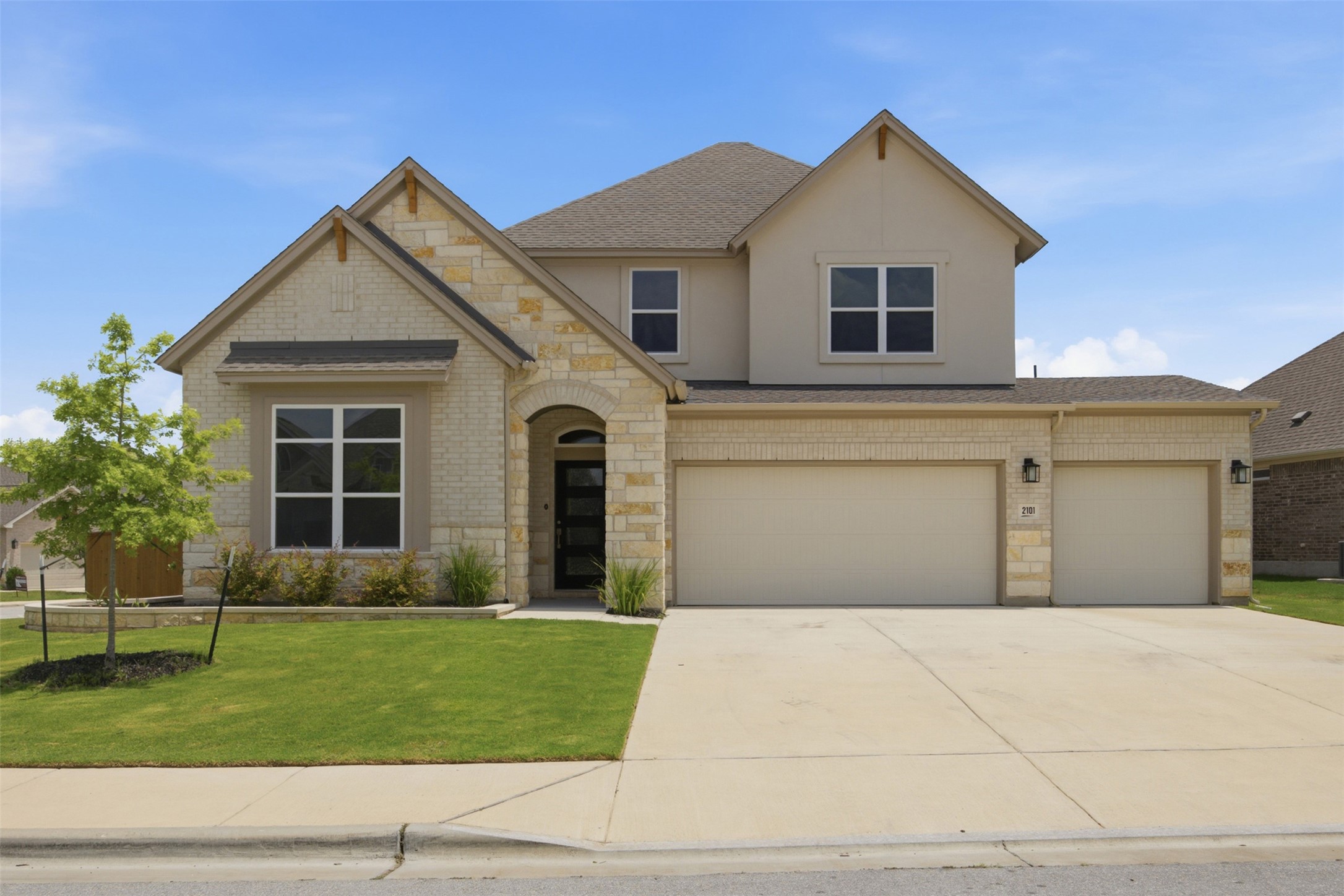 2101 Little Snake Way Georgetown, TX 78633 - Photo 2 of 37 A welcoming facade showcases a seamless blend of brick and stucco with an inviting arched entry and dual garage doors.