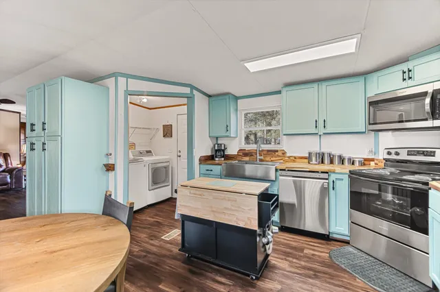 a kitchen with stainless steel appliances granite countertop a stove top oven a sink dishwasher a refrigerator and cabinets with wooden floor