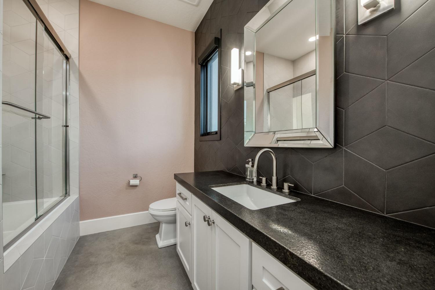 3895 East Reno Avenue Clovis, CA 93619 - Photo 34 of 67 a bathroom with a granite countertop sink a toilet and a mirror