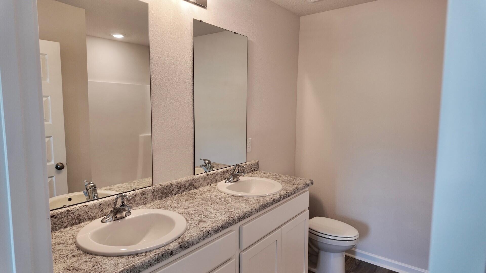 6356 Firefly Drive Milton, FL 32583 - Photo 19 of 44 a bathroom with a granite countertop sink a toilet and a mirror