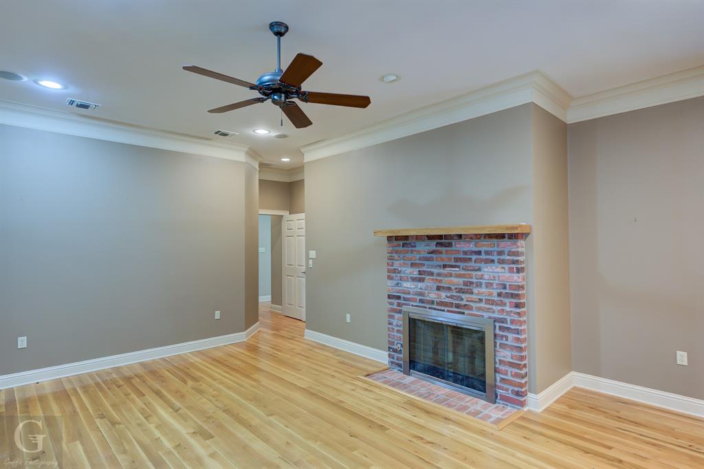 1212 WPA Road Homer, LA 71040 - Photo 21 of 35 Unfurnished living room with crown molding, wood finished floors, ceiling fan, baseboards, and a fireplace