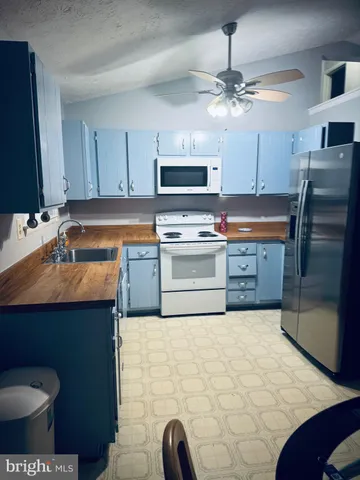 a kitchen with stainless steel appliances a sink a stove a refrigerator cabinets and a dining table