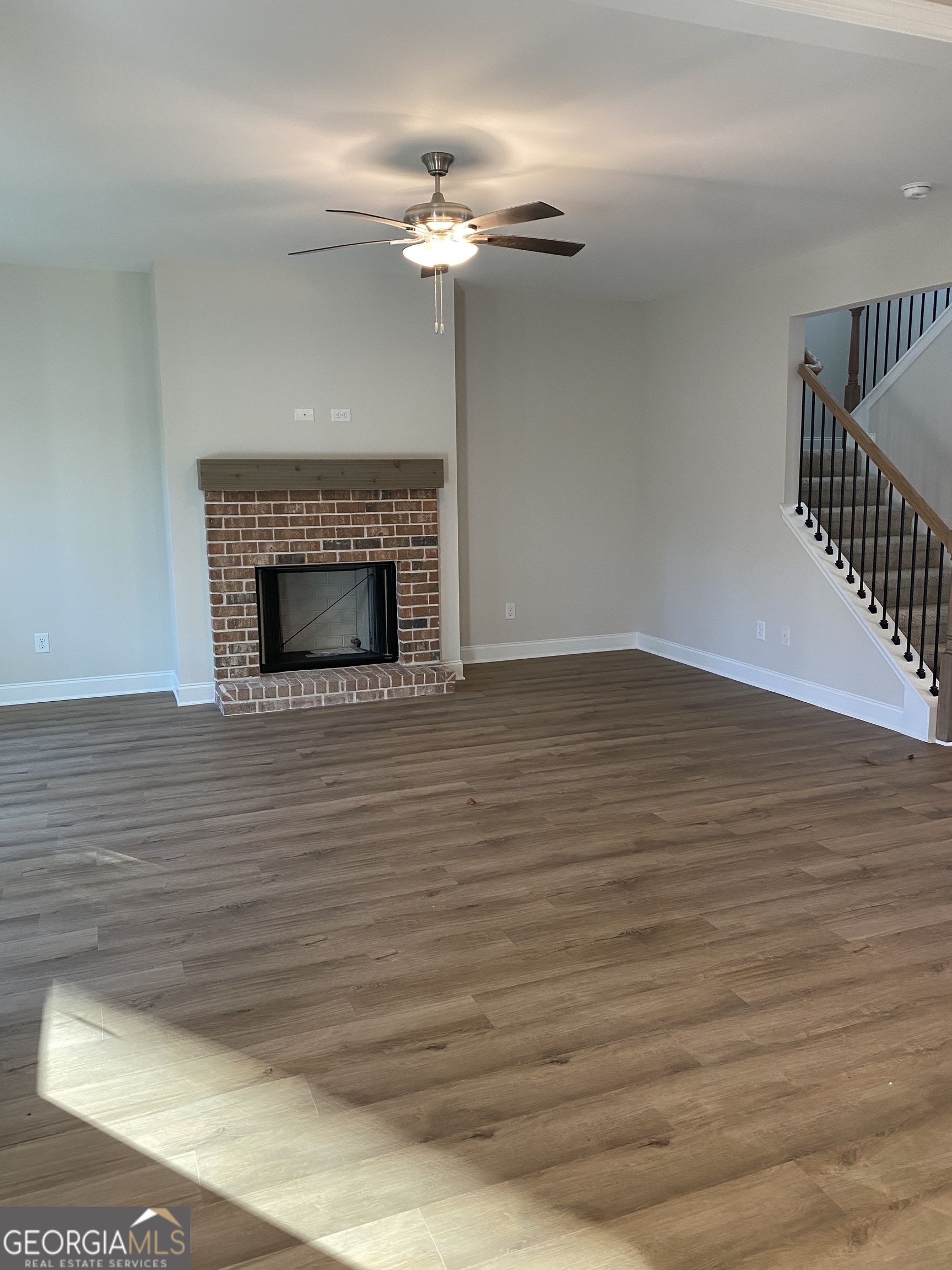 162 Delightful Way, Unit 28 Winder, GA 30680 - Photo 2 of 11 a view of an empty room with wooden floor fireplace and a window