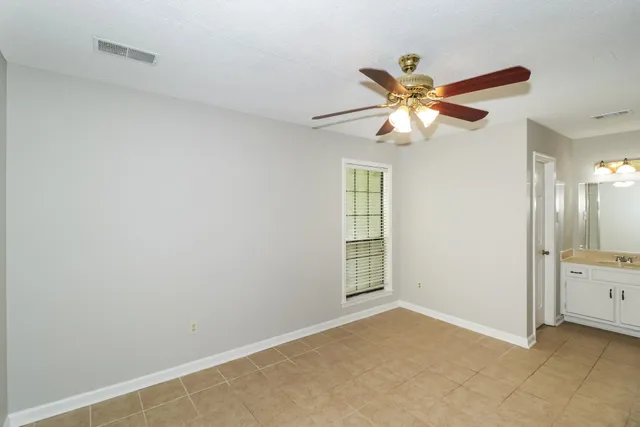 a view of an empty room and window with a chandelier fan