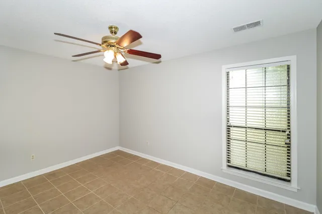 an empty room with windows and fan