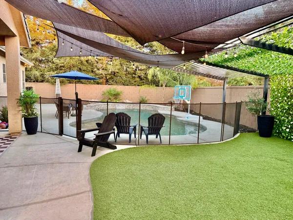 a view of a patio with table and chairs under an umbrella with a small yard