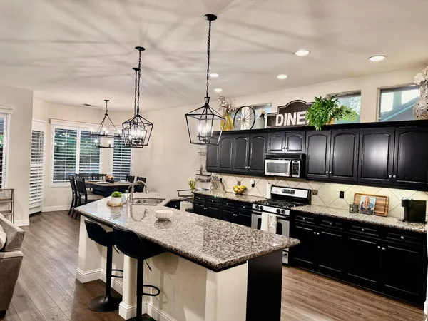 a kitchen with a kitchen island stainless steel appliances a sink stove and living room view