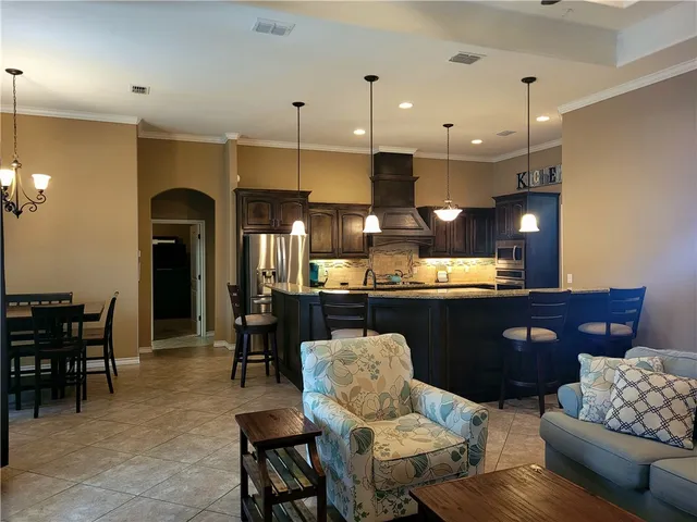 a living room with furniture kitchen view and a chandelier