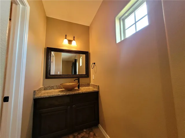 a bathroom with a granite countertop sink and a mirror