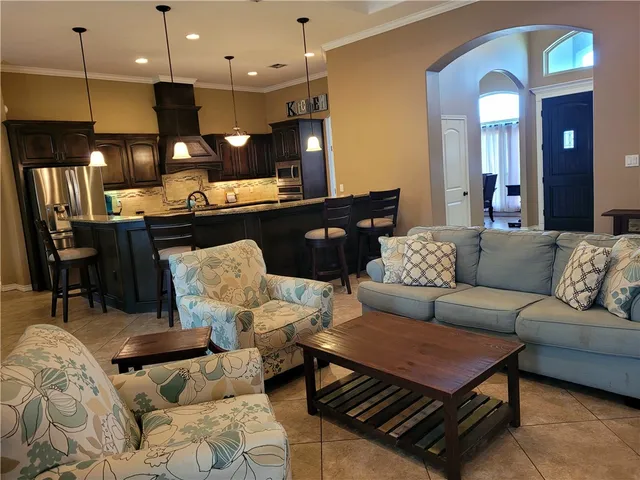 a living room with furniture kitchen view and a wooden floor